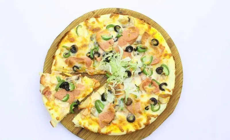 پیتزا مخلوط خوش‌طعم فست‌فود کافی 72 با پنیر طلایی، زیتون سیاه، فلفل دلمه سبز، برش‌های کالباس و کاهو تازه، روی سینی چوبی آماده سرو.