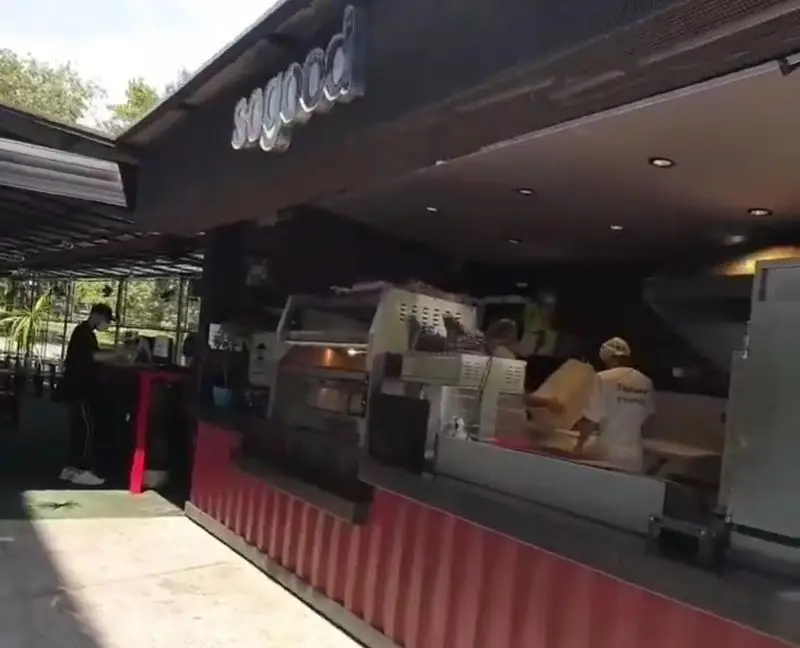 نمایی از شعبه کی اف سی سوگود ولیعصر، با پیشخوان قرمز و پرسنل فعال در حال تهیه غذا. رستوران فست فود مدرن و محبوب در تهران.