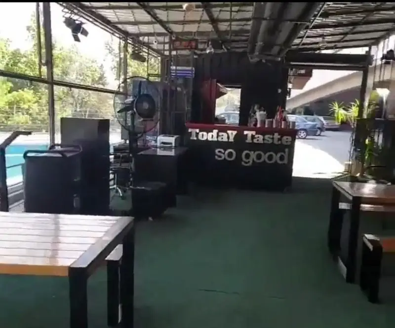 محیط داخلی کی اف سی سوگود ولیعصر، با دکوراسیون مدرن، میز و صندلی چوبی و پیشخوان "Today Taste so good" برای تجربه غذای لذت‌بخش.