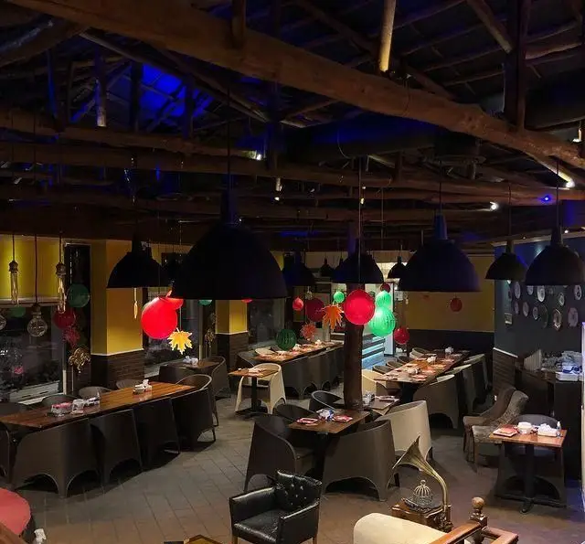 فضای داخلی زیبا و سنتی سرای سنتی دفینه، با میزهای چوبی شیک، صندلی‌های راحت و نورپردازی گرم، محیطی دلنشین برای مشتریان.