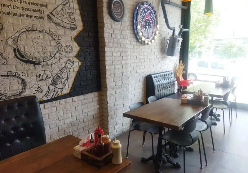 دکوراسیون مدرن و گرم کافه رستوران ایتالیایی دیبارو، با دیوارهای آجری طرحدار، نقاشی‌های دیواری خلاقانه و چیدمان راحت میز و صندلی.