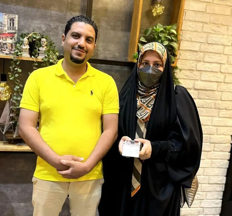 بازدید از کافه رستوران ایتالیایی دیبارو، مردی با پیراهن زرد لبخند می‌زند و زنی با حجاب و ماسک جعبه‌ای در دست دارد.