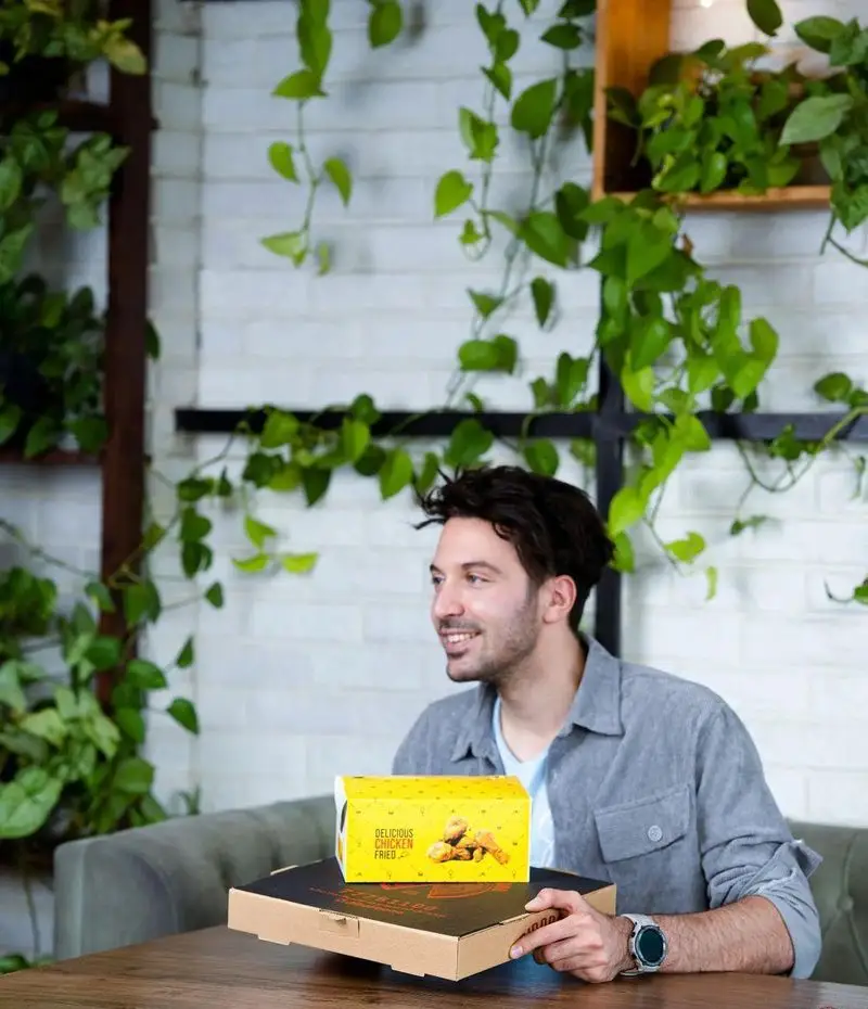 کافه رستوران ایتالیایی دیبارو: مشتری در حال لذت بردن از فضای سبز و آرام، همراه با غذای لذیذ شامل پیتزا و مرغ سوخاری.