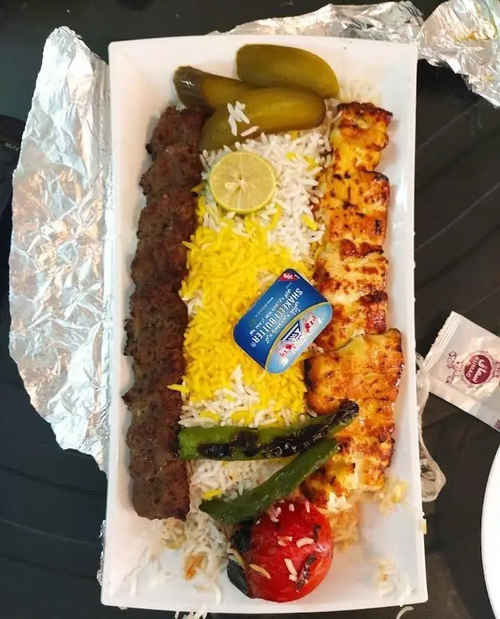 رستوران انتظامی: غذای لذیذ شامل کباب کوبیده، جوجه کباب، برنج زعفرانی، گوجه کبابی و خیارشور. تجربه یک وعده کامل و خوشمزه ایرانی.