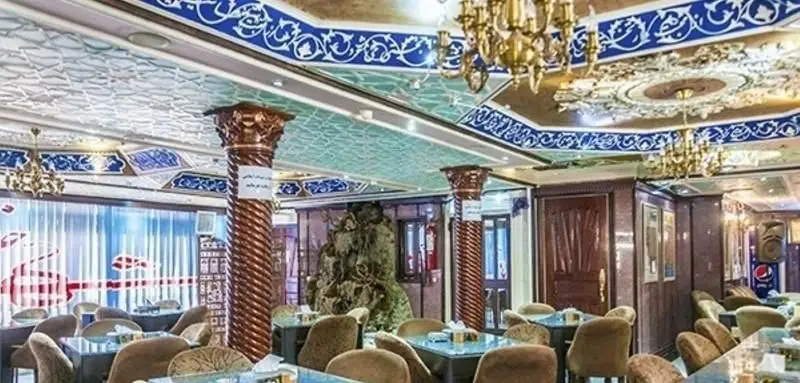 تصویری از فضای داخلی رستوران ایرانی شهرزاد با طراحی سنتی و سقف‌های مجلل، لوسترهای طلایی و میز و صندلی‌های شیک و راحت.