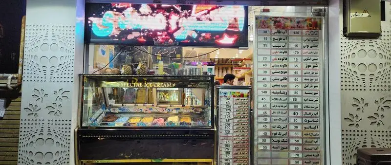 نمای بیرونی مغازه بستنی و فالوده اکبر مشهدی با نمایشگر بستنی‌های رنگارنگ، منوی کامل انواع دسر و آبمیوه و دکوراسیون مدرن