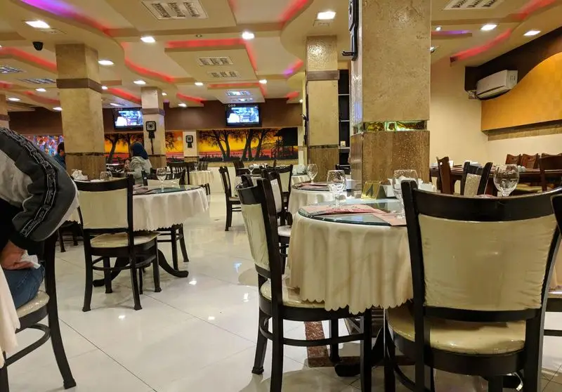 تصویری از فضای داخلی دلنشین و دکوراسیون زیبای رستوران اکبر جوجه با چیدمان منظم میزها و محیطی آرام برای پذیرایی.