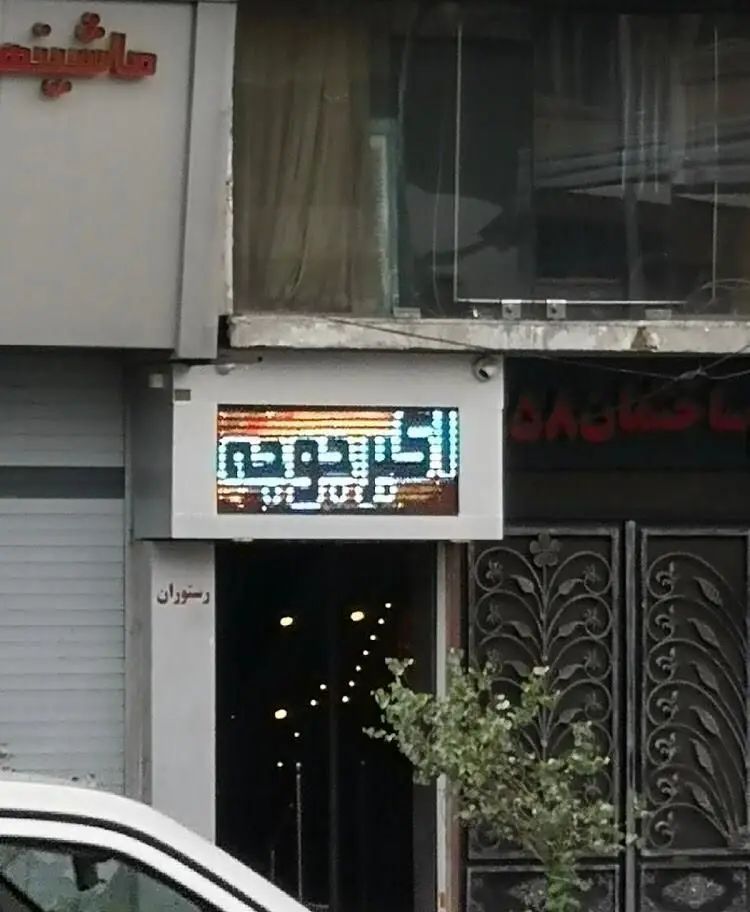 نمای بیرونی و تابلوی درخشان LED رستوران اکبر جوجه که نام آن را به وضوح نمایش می‌دهد، همراه با ورودی دعوت‌کننده.