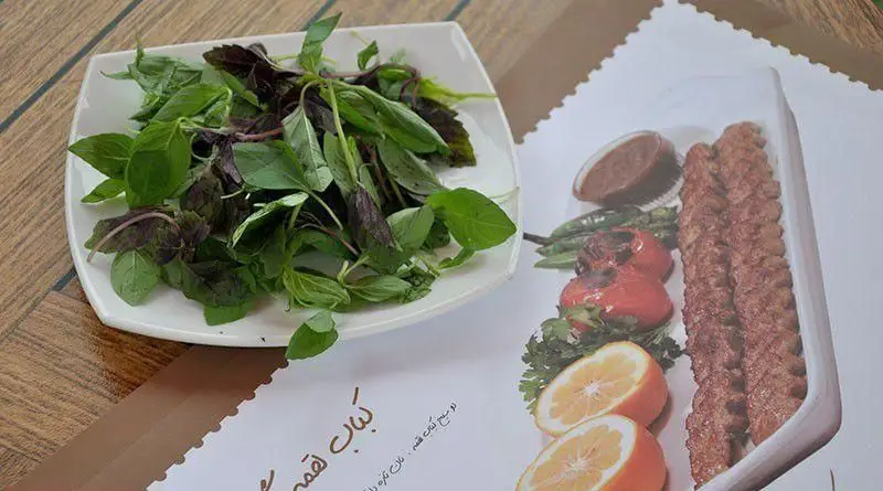 نمایی نزدیک از کباب لقمه شمرون کباب به همراه سبزی خوردن تازه، گوجه و فلفل کبابی، لیمو و سس مخصوص. لذت طعم اصیل ایرانی در رستوران شمرون.