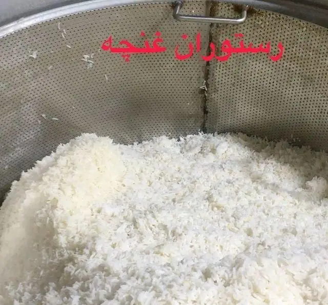 مقدار زیادی برنج سفید و پخته شده در ظرف مخصوص، آماده سازی غذای اصیل ایرانی در رستوران غنچه برای مشتریان.