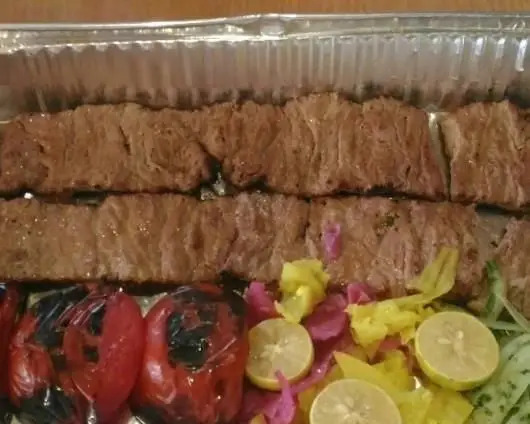 کباب کوبیده لذیذ رستوران پارک نارمک در ظرف بیرون بر، به همراه گوجه کبابی، لیمو و مخلفات تازه. غذای اصیل ایرانی.