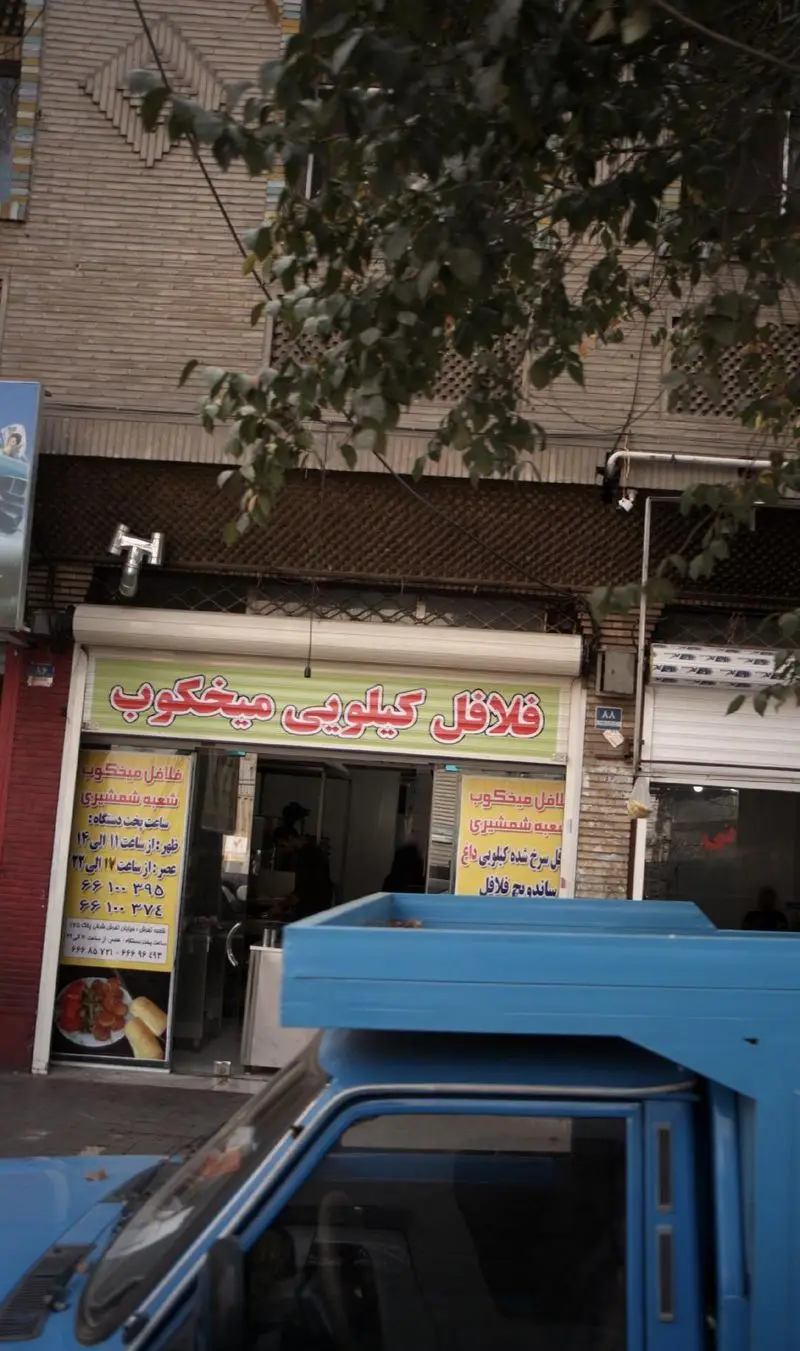 نمای بیرونی مغازه فلافل کیلویی میخکوب، شعبه شمشیری، با تابلوی روشن ارائه دهنده فلافل داغ و ساندویچ فلافل.