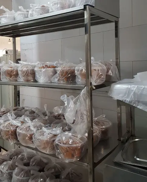 نمایی از آماده سازی و بسته بندی بهداشتی فلافل کیلویی میخکوب، شامل تعداد زیادی ظرف فلافل در کیسه‌های پلاستیکی روی قفسه‌ها.