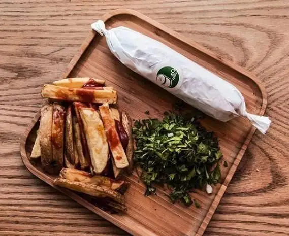 ساندویچ رول بزرگ با لوگوی اغذیه فروشی نمک، سیب‌زمینی وجز با سس کچاپ و سبزیجات خرد شده روی سینی چوبی آماده سرو.