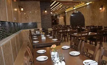 تصویر فضای داخلی رستوران عمارت، با چیدمان شیک میزها و دکوراسیون دلنشین. محیطی آرام و ایده‌آل برای صرف وعده‌های غذایی در فضایی خاطره‌انگیز.