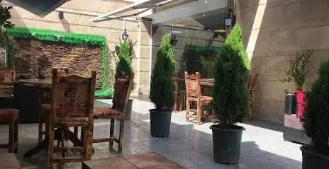 محیط آرام و دلپذیر فضای باز کافی شاپ پالمیرا، دارای مبلمان چوبی راحت و گلدان‌های زیبا، انتخابی عالی برای اوقات فراغت شما.