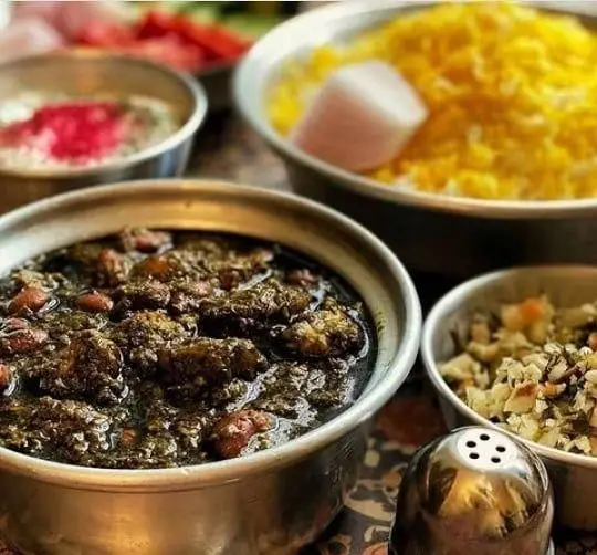 سفره‌ای از غذاهای اصیل و سنتی ایرانی در رستوران طهورا: قورمه سبزی با برنج زعفرانی، ماست و خیار و دورچین‌های متنوع و تازه.