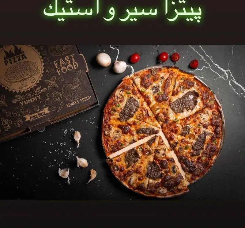 پیتزا سیر و استیک کافه دیدارو: یک پیتزای تازه و خوشمزه با قارچ، سیر و تکه‌های گوشت استیک در کنار جعبه آماده سرو.