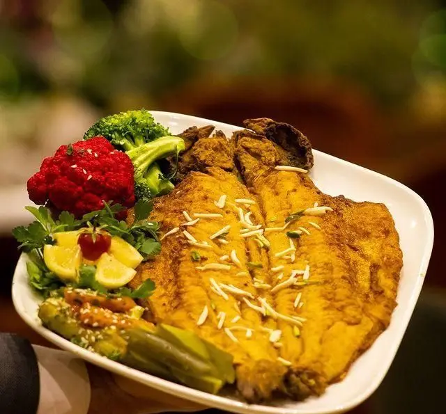 بشقاب ماهی سرخ شده طلایی با بادام، گل کلم قرمز، بروکلی، لیمو، سبزیجات و مخلفات لذیذ رستوران بین المللی ۱۳۳.