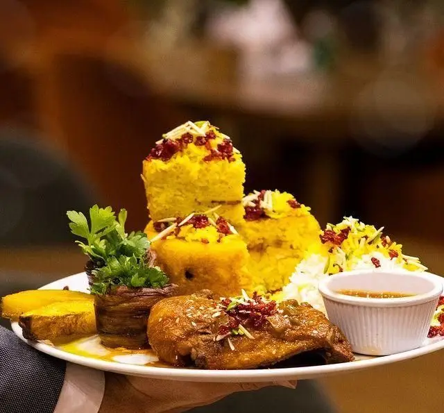 بشقاب غذای لوکس رستوران بین المللی ۱۳۳: ته چین، زرشک پلو با مرغ بریان، سیب زمینی و سبزیجات تازه. طعم اصیل غذای ایرانی.