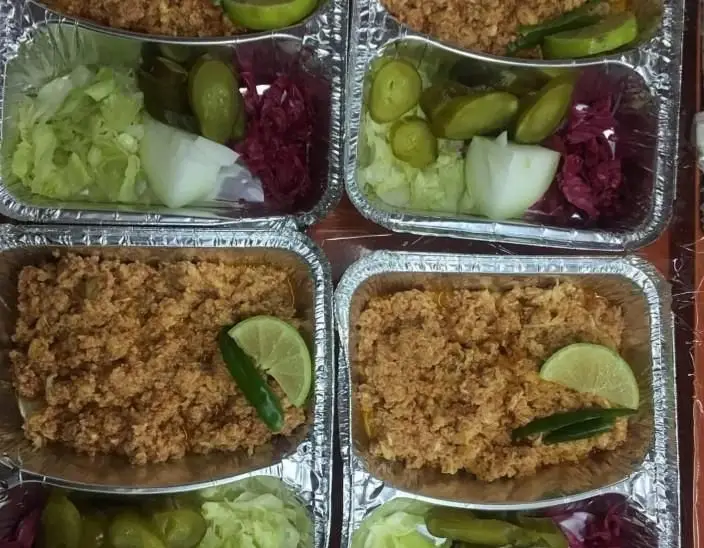 رستوران ایرانی اسلو فود پایتخت: غذای بسته بندی شامل پلو مخلوط با گوشت، لیمو، فلفل، و سالاد کاهو، پیاز، خیارشور و کلم قرمز.