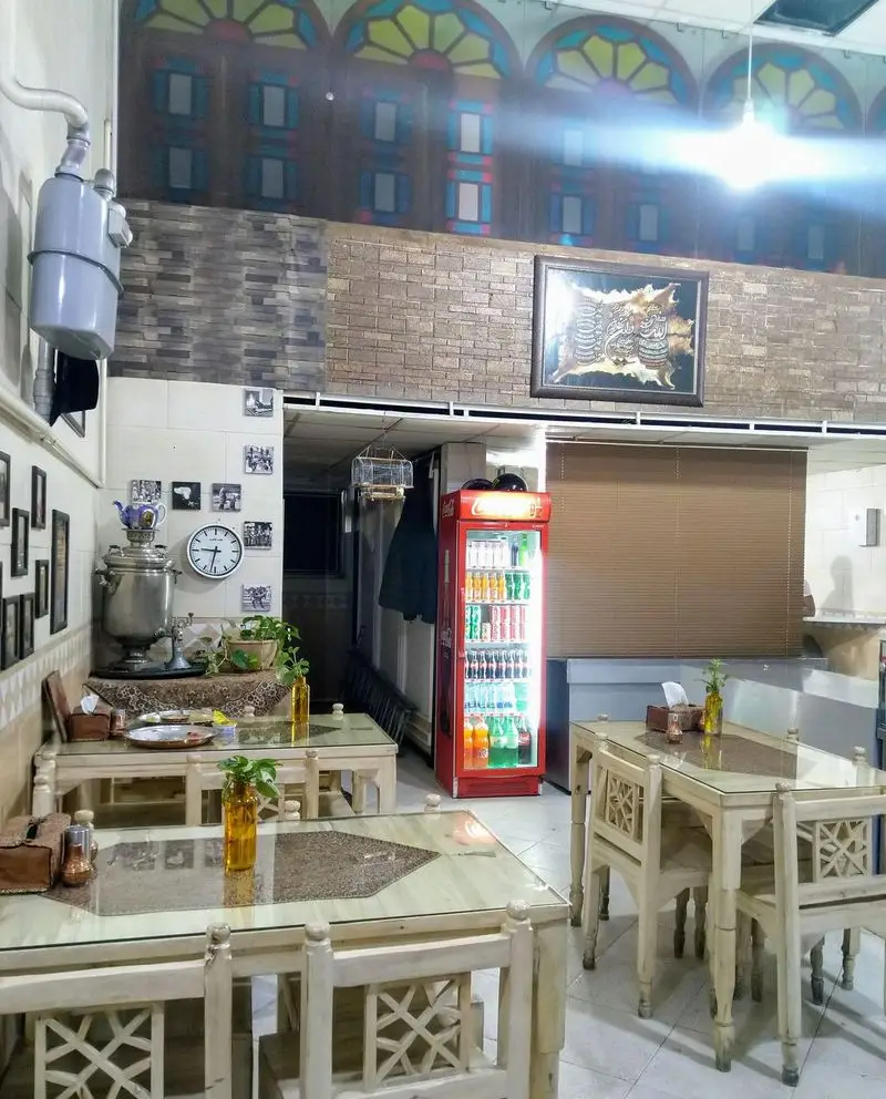 دکوراسیون داخلی زیبای رستوران دایی رضا، شامل میز و صندلی‌های چوبی و سنتی، سماور ایرانی و یخچال نوشیدنی متنوع.