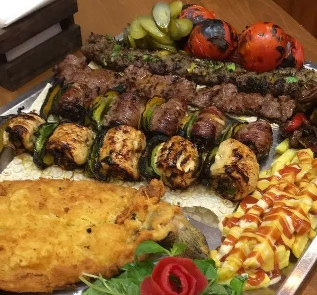 سینی غذای متنوع کافه رستوران پاشا: انواع کباب (جوجه، کوبیده)، کباب لقمه، ماهی سوخاری، سیب زمینی سرخ کرده و مخلفات تازه.