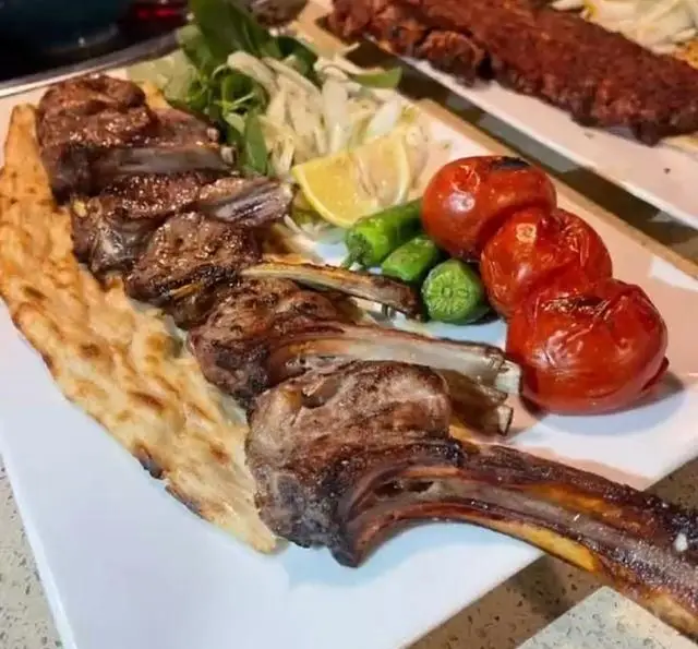 شیشلیک دنده کباب خوشمزه و آبدار کافه رستوران پاشا با گوجه و فلفل کبابی، نان داغ، انتخابی عالی برای دوستداران غذای اصیل ایرانی.