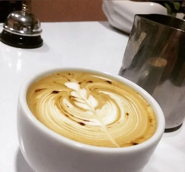 یک فنجان لاته هنرمندانه با لاته آرت زیبا، سرو شده در کافه رستوران پاشا. لذت یک نوشیدنی عالی در محیطی دلنشین.