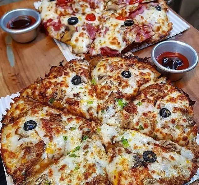 دو پیتزا خوشمزه و داغ از کافه رستوران پاشا با تاپینگ قارچ، پنیر، زیتون، سوسیس و گوجه فرنگی آماده سرو با سس.