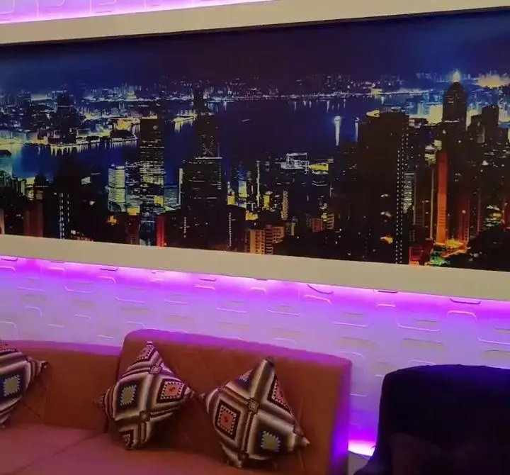 دکوراسیون داخلی جذاب کافه رستوران پاشا با منظره پانورامیک شهر در شب، نورپردازی مدرن بنفش LED و مبلمان راحت برای تجربه ای دلپذیر.