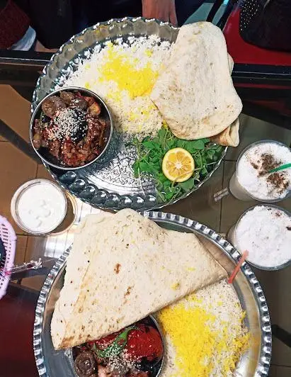 سفره سنتی کباب نارنج با کباب، برنج زعفرانی، نان تازه، سبزی و لیمو. وعده غذایی لذیذ ایرانی در رستوران کباب نارنج.