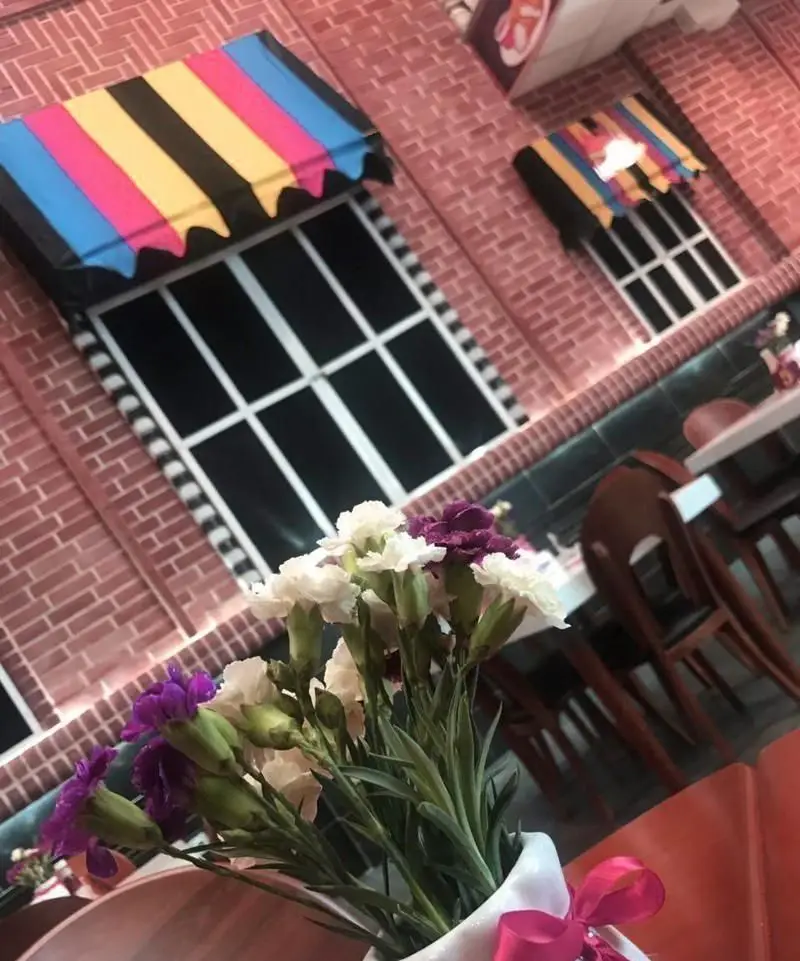 فضای داخلی مدرن و دلنشین فست فود هات برگر با دکوراسیون دیواری آجری، پنجره‌های خاص و گل‌های زیبا روی میزها، محیطی ایده‌آل برای صرف غذا.