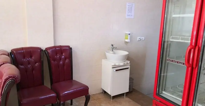 فضای داخلی تمیز و مرتب رضا لقمه با صندلی‌های راحت چرمی قرمز، سینک بهداشتی برای مشتریان و یخچال نوشیدنی آماده سرویس‌دهی.