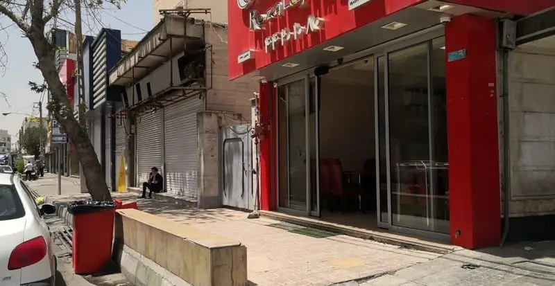 نمای خارجی رستوران رضا لقمه در یک خیابان شهری، با تابلو قرمز رنگ، درب‌های شیشه‌ای اتوماتیک و پیاده‌رو.