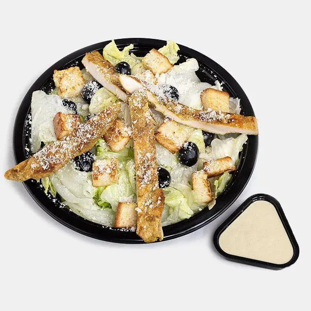 عکس سالاد سزار باروس برگر، حاوی تکه‌های مرغ گریل، کروتون، زیتون و پنیر رنده شده. سس مخصوص در کنار.