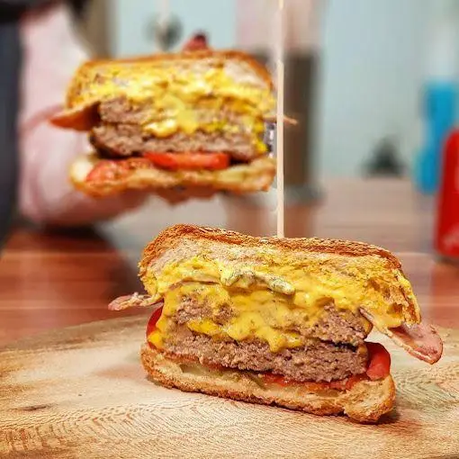 ساندویچ برگر دوبل و پنیر ذوب‌شده از باروس برگر. این همبرگر با دو لایه گوشت، پنیر زیاد، بیکن و گوجه، انتخابی ایده‌آل برای دوستداران فست‌فود است.