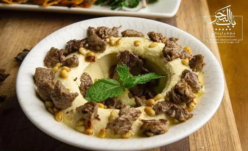 حمص با گوشت و دانه کاج، یک غذای خوشمزه و سنتی لبنانی از منوی رستوران باب البحر، ایده‌آل برای دوستداران غذاهای اصیل خاورمیانه.