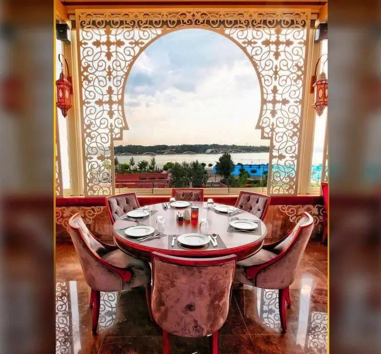 فضای داخلی شیک و لوکس رستوران لبنانی باب البحر با میز غذاخوری مجلل، دکوراسیون عربی و منظره زیبا رو به آب، آماده میزبانی مهمانان.