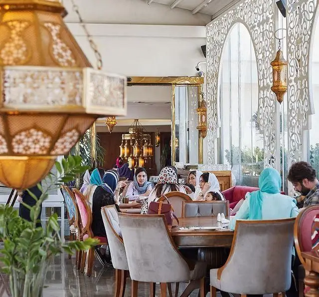مشتریان در فضای داخلی شیک و مدرن رستوران لبنانی باب البحر با دکوراسیون خاص خاورمیانه‌ای و فانوس‌های زیبا، در حال غذا خوردن هستند.