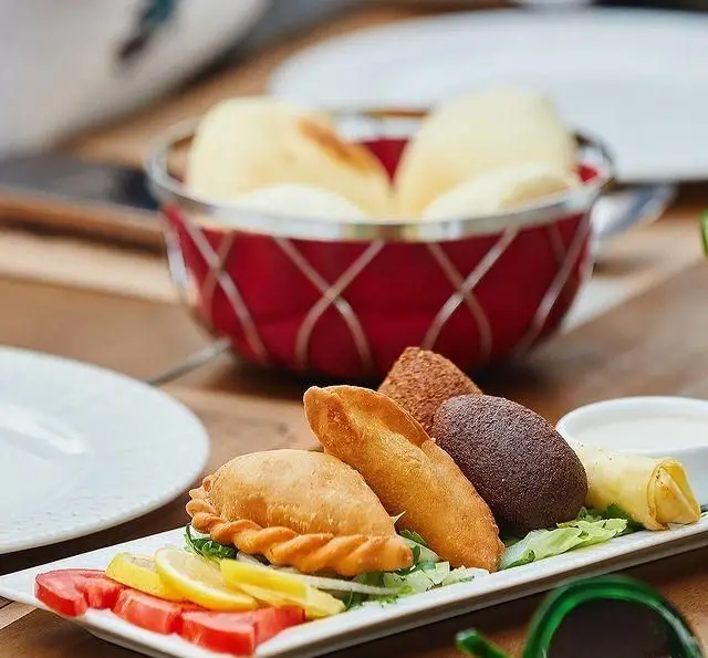 سینی متنوعی از مزه‌های محبوب لبنانی شامل سمبوسه، کبه و لقمه‌های خوشمزه در رستوران لبنانی باب البحر. ایده‌آل برای یک وعده عالی.