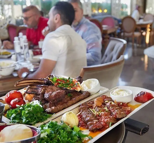 پلاتر جذاب کباب و گوشت گریل شده متنوع شامل دنده و کباب کوبیده با سبزیجات تازه در رستوران لبنانی باب البحر برای تجربه غذای اصیل.
