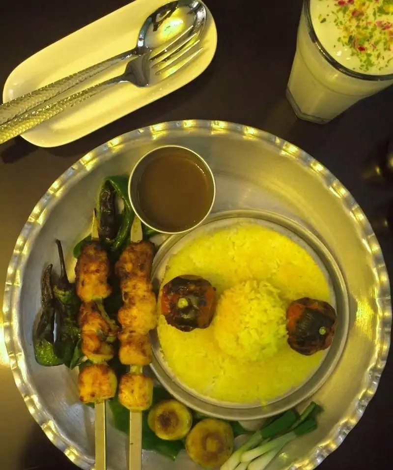 یک سینی کامل غذای ایرانی شامل چلو جوجه کباب، برنج زعفرانی، گوجه، فلفل و قارچ کبابی به همراه دوغ سنتی در کافی شاپ پرسوناژ.