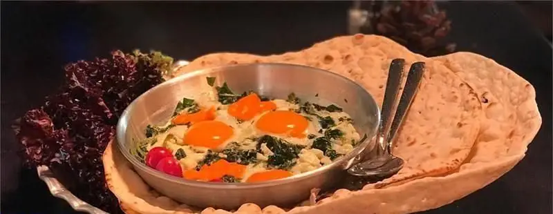 صبحانه دلپذیر کافی شاپ پرسوناژ شامل املت یا نرگسی تخم مرغ با سبزیجات تازه، گوجه گیلاسی و نان داغ در محیطی دلنشین.