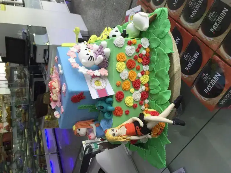 کیک خاص شیرینی لادن طلایی، مزین به فوندانت آبی و سبز، شامل فیگور هلو کیتی، پری دریایی و عروسک دخترانه برای جشن تولد.