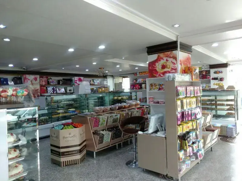 شیرینی لادن طلایی، بهترین شیرینی فروشی با ویترین‌های متنوع از کیک، شیرینی تازه و شکلات برنوتی در فضایی مدرن و زیبا.