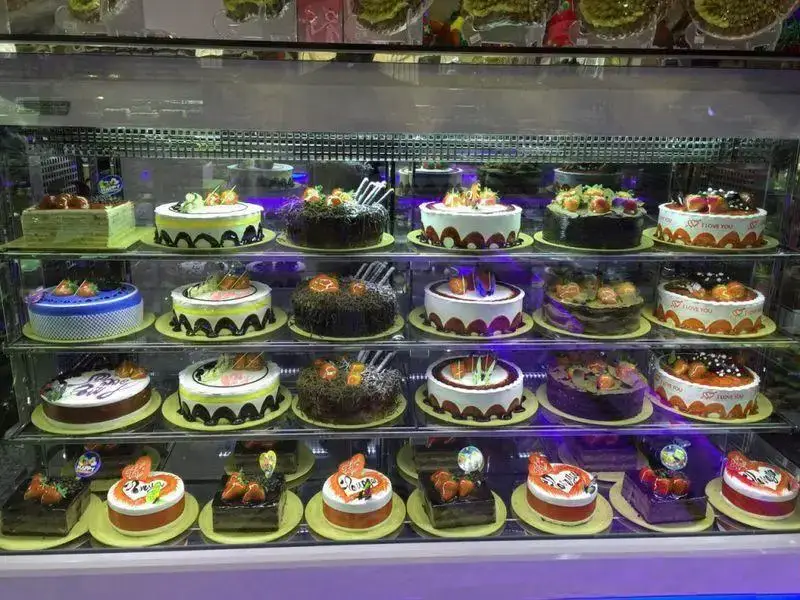 تصویری از ویترین شیرینی لادن طلایی حاوی انواع کیک‌ها و شیرینی‌های تازه و خوشمزه، با تزئینات زیبا و مناسبتی برای جشن‌ها و مراسم.