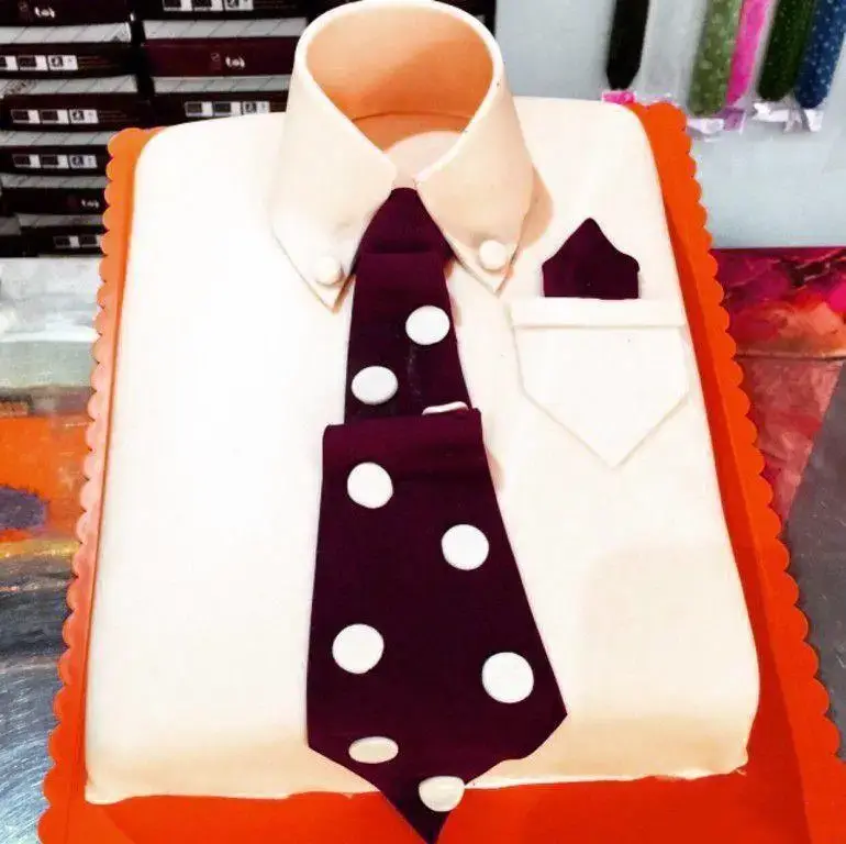کیک تولد مردانه به شکل پیراهن سفید با کراوات زرشکی خال‌دار و دستمال جیبی، مناسب روز پدر از شیرینی لادن طلایی.