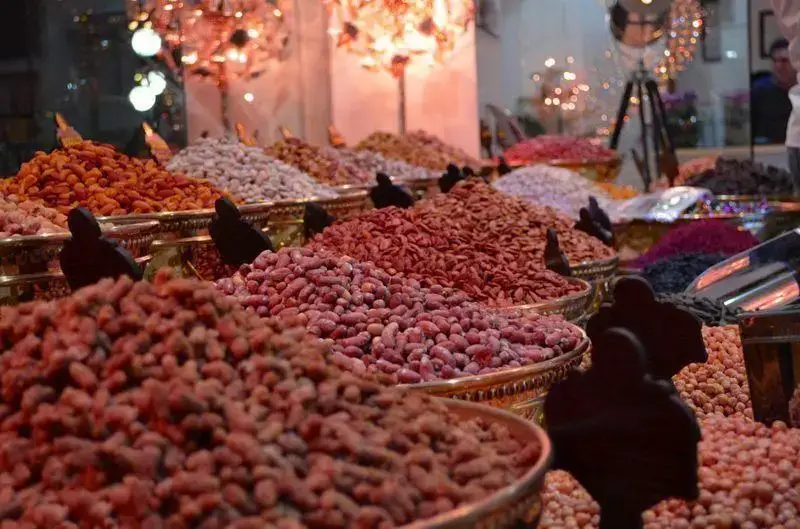 نمایی نزدیک از سینی های پر آجیل و خشکبار متنوع و رنگارنگ در فروشگاه شیرینی لادن طلایی با کیفیت عالی و تازه برای یلدا.