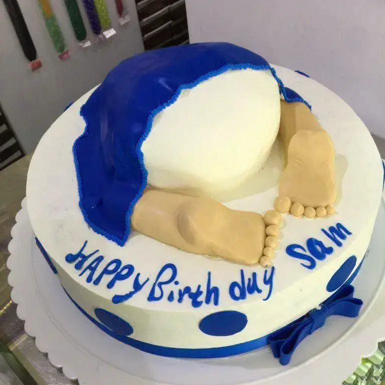 کیک تولد فانتزی و خاص شیرینی لادن طلایی با طرح سر به زیر و پاهای بیرون زده، رنگ آبی و سفید، مناسب تولد سام.